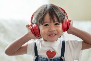 Young child smiling while wearing red headphones